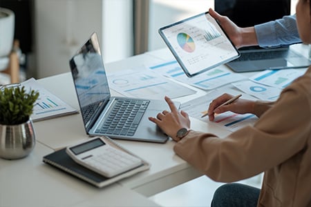 Business team analyzing financial data with laptop and tablet