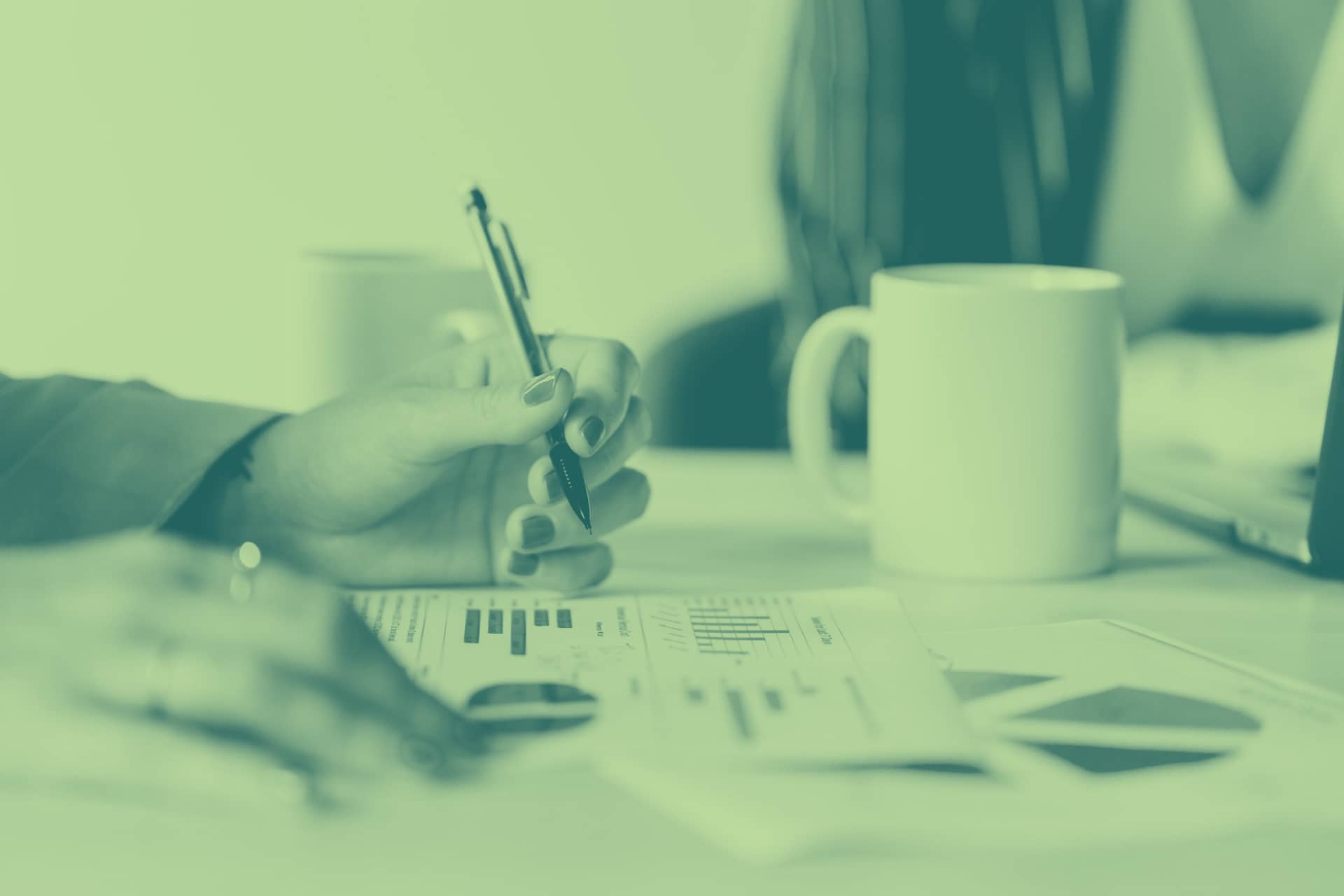 Hand holding a pencil working on financial documents
